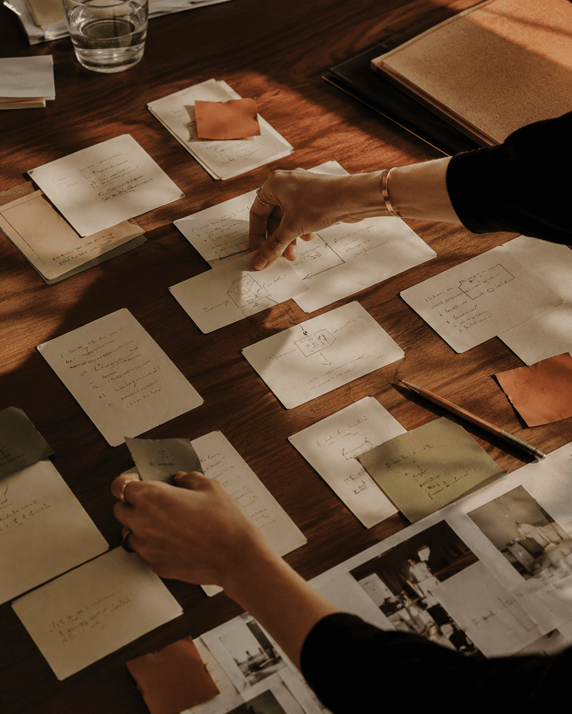 Hands arranging handwritten reference notes on a desk