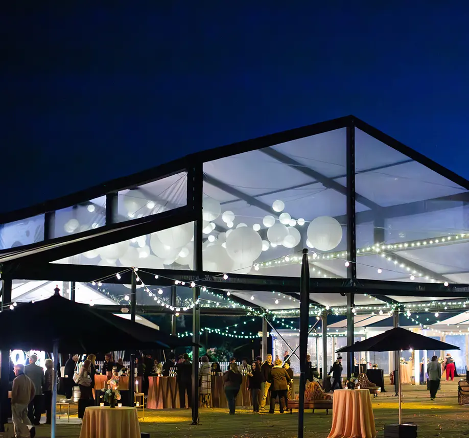 A clear-tent event installation glowing at night